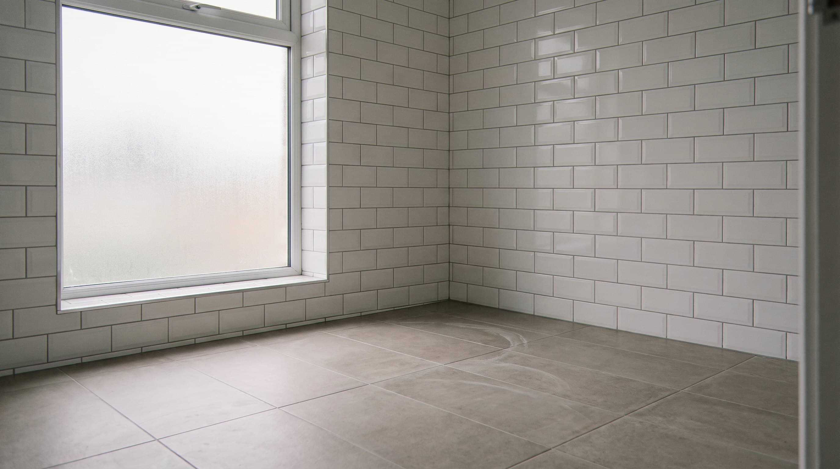 Freshly tiled white subway walls in an empty bathroom