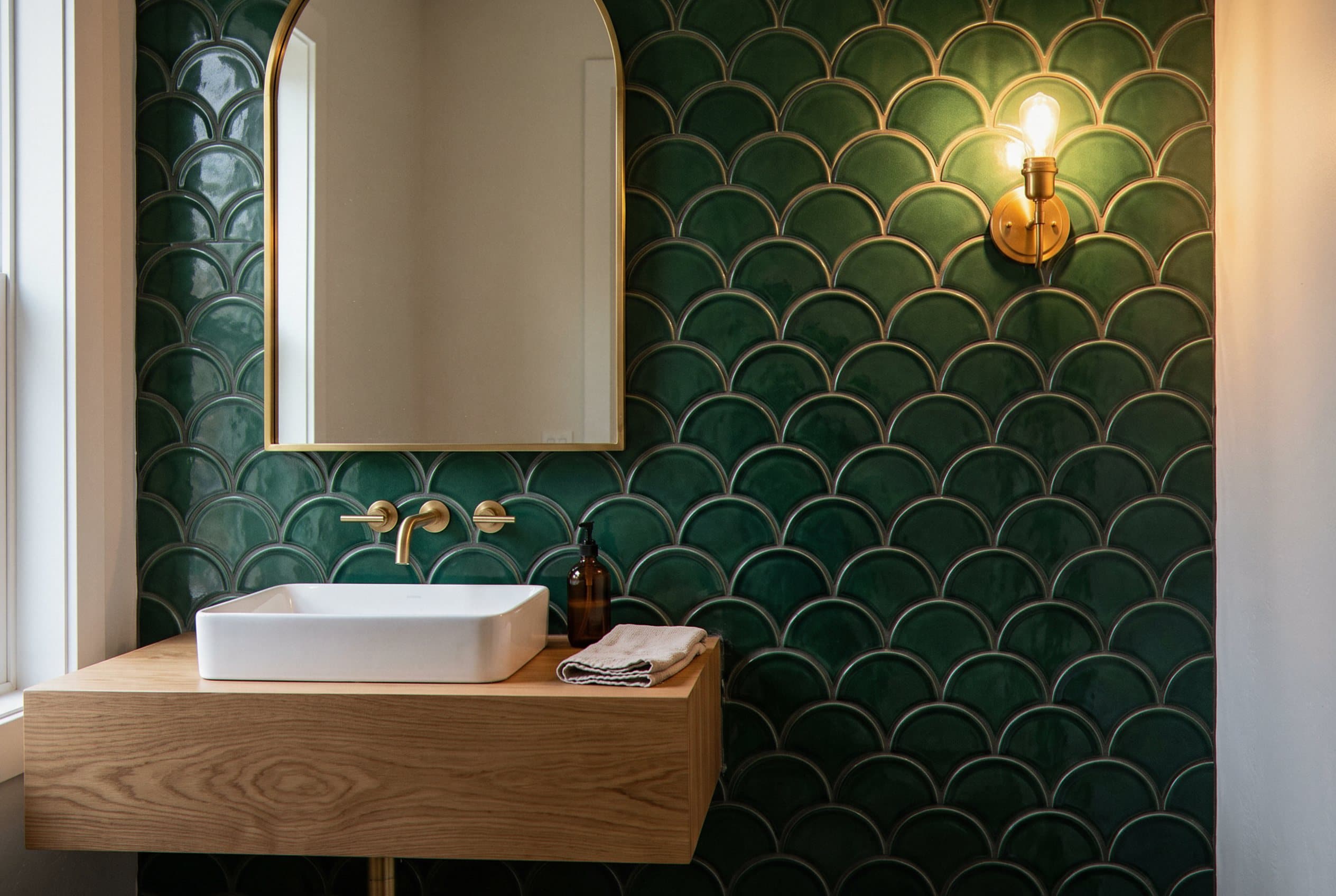 Green scalloped tile accent wall behind a vessel sink