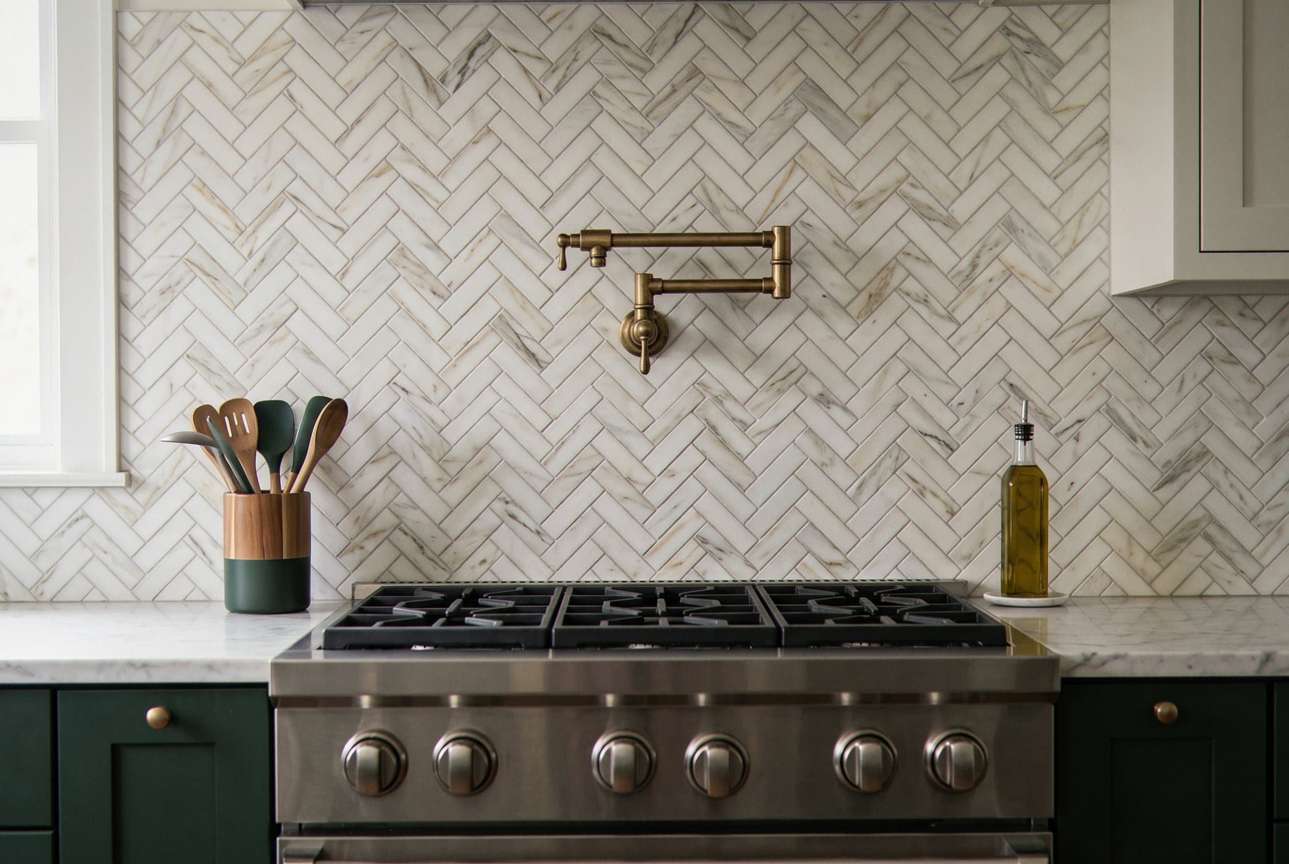 Marble herringbone backsplash with a brass pot filler