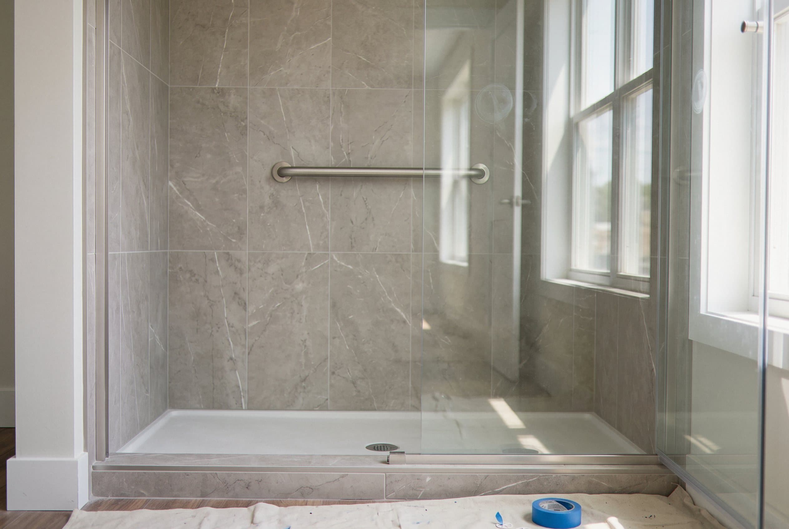 Gray marble-look shower with a glass door and grab bar